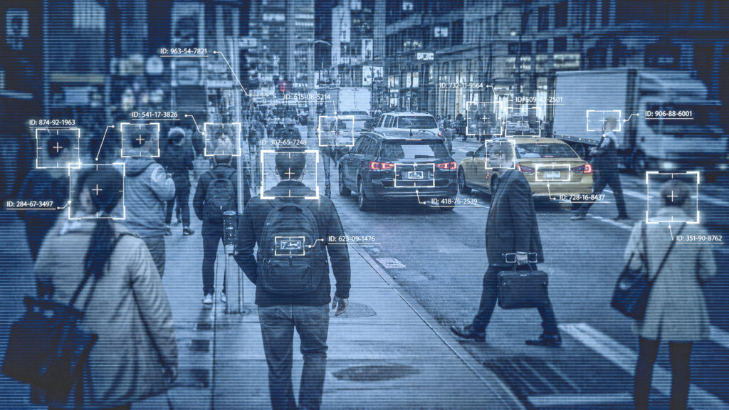 Busy city street with pedestrians and cars, overlaid by facial-recognition boxes and ID numbers identifying people.